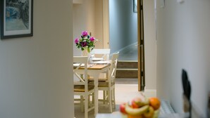 A dining area with a table set for two, a vase of flowers, and a fruit bowl on the table. - Eske Holiday Apartment (Donegal Town)