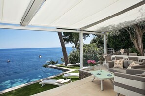 Une terrasse avec vue sur la mer, des meubles d’extérieur et une piscine.