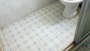A bathroom with a toilet, a hand dryer, and patterned floor tiles. - Top Lodge (Naivasha)