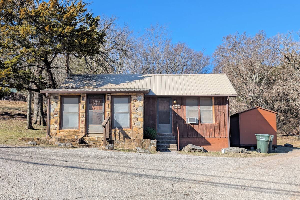 A rustic cabin with a stone facade, wooden exterior, and a metal roof.