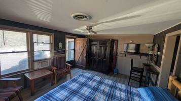 A bedroom with a bed, a chair, a desk, a ceiling fan, and a window with blinds.