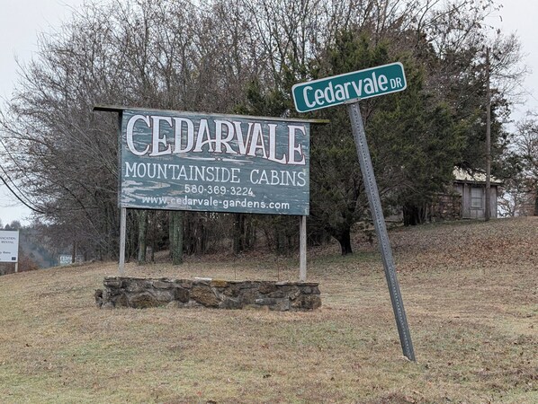 Letrero de Cedarvale Mountain Inside Cabins con información de contacto y una página web.