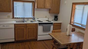 A kitchen with wooden cabinets, a stove, a sink, and a ceiling fan.