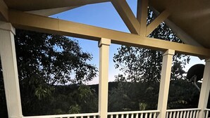 A wooden deck with white railings and a clear view of trees and hills in the background. - Cedarvale Cabins at Turner Falls (Davis)
