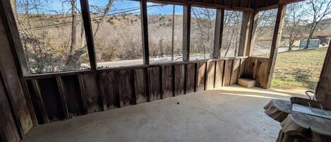A rustic wooden room with large windows, a concrete floor, and a wooden bench.