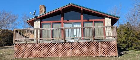 Une cabane dotée d’une terrasse en bois, d’une cheminée en pierre et d’une pancarte indiquant qu’il s’agit de la cabane numéro 5.