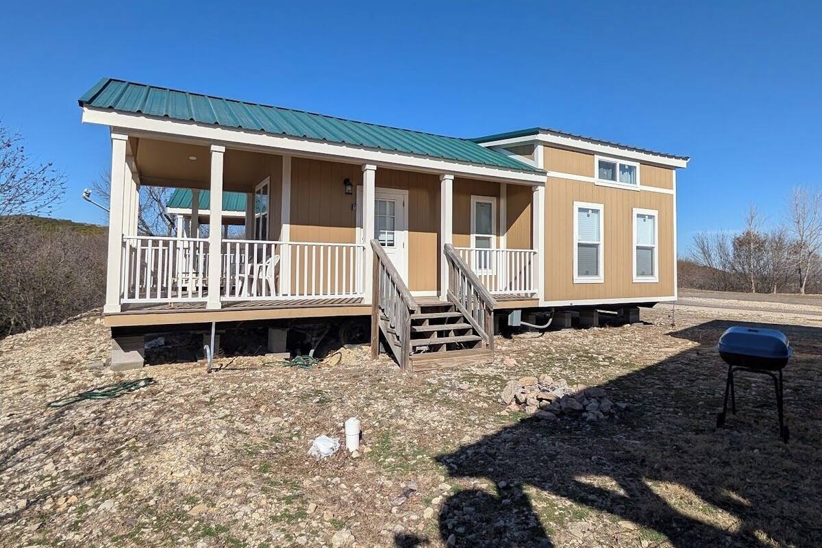 A two-story mobile home with a porch and a covered outdoor area.