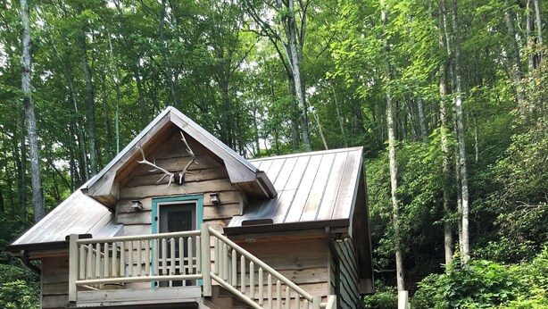 Eine Holzhütte mit Balkon, Treppe und Steinfundament.