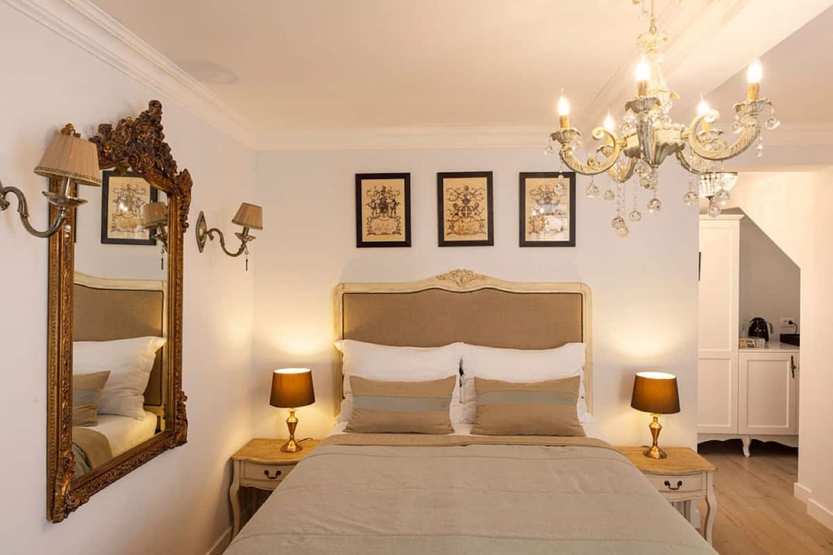 A bedroom with a large ornate mirror, a four-poster bed, and a chandelier.