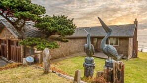 A wooden building with a sloped roof, a pine tree, and two bird sculptures. - Oceanfront Whale Watching Retreat (Depoe Bay)
