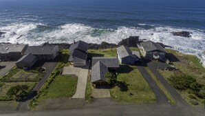 An aerial view of a coastal residential area with houses, a road, and the ocean. - Oceanfront Whale Watching Retreat (Depoe Bay)