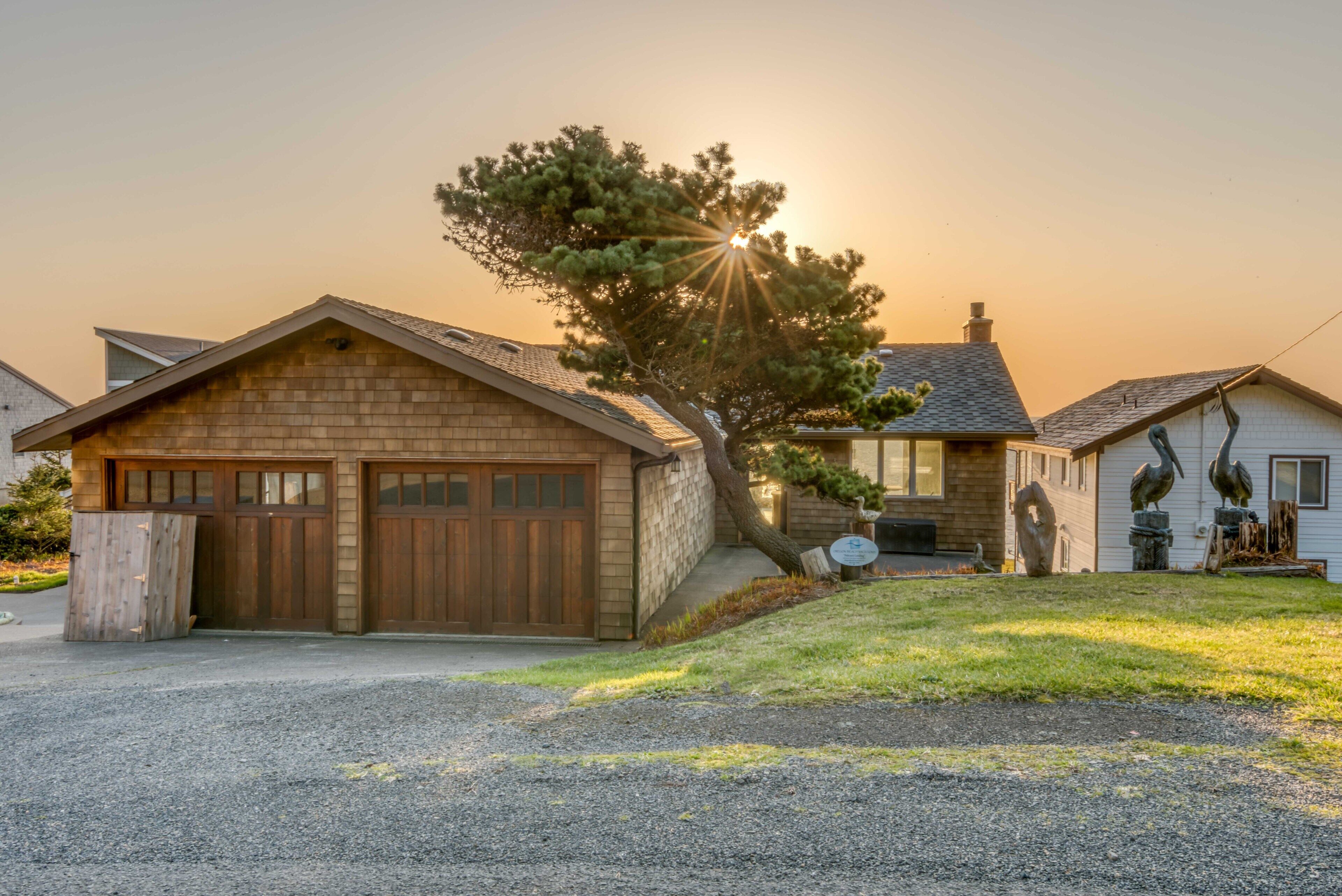 A two-story house with a garage, a tree in front, and a clear sky.