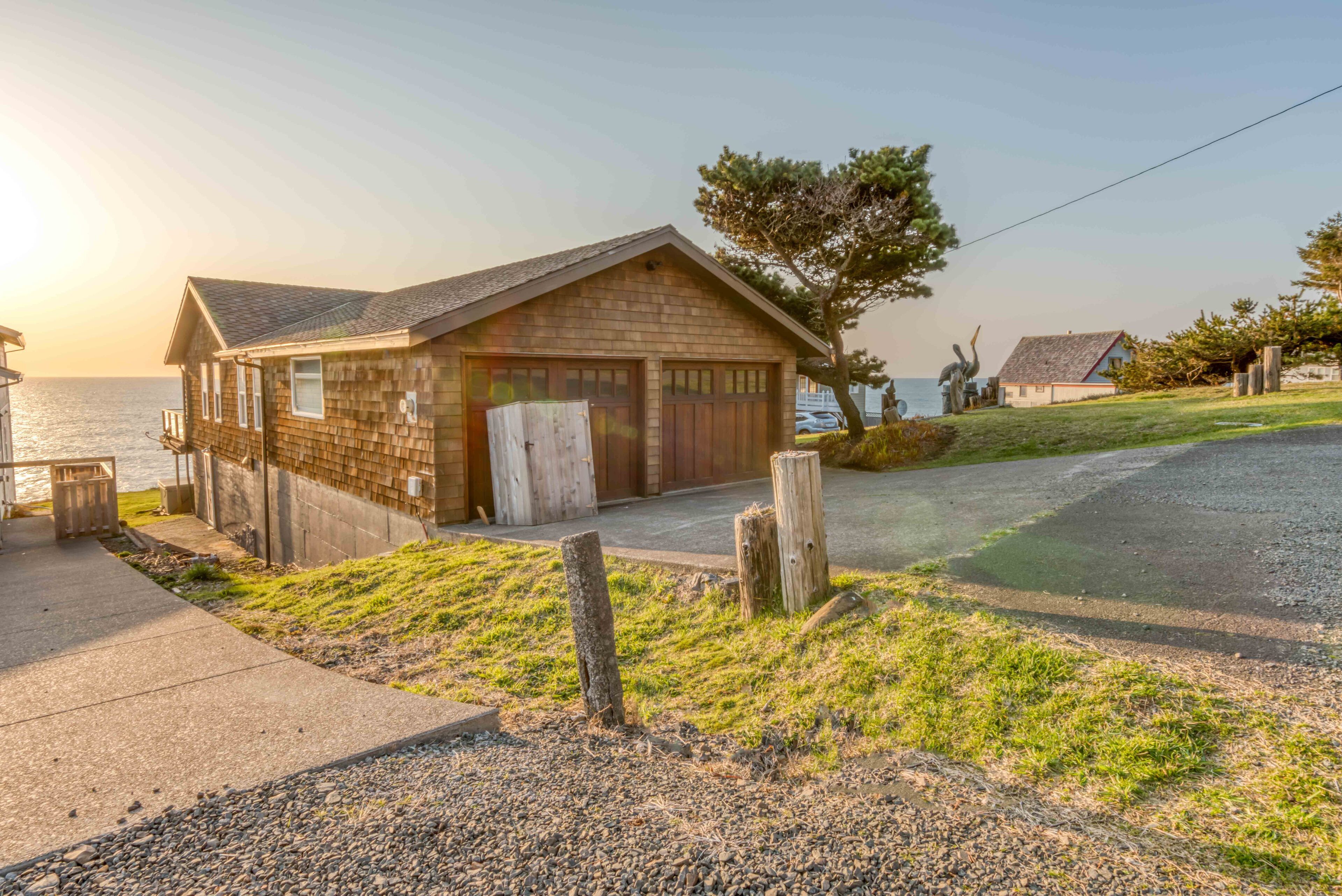 A coastal house with a garage, a grassy yard, and a view of the sea.