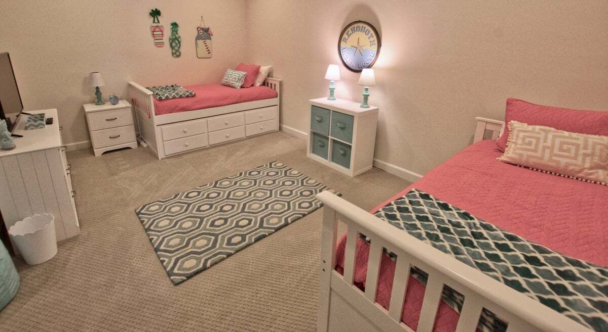 A bedroom with a bed, nightstands, a dresser, a patterned rug, and a wall clock.