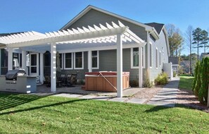 Une maison d’habitation dotée d’un patio couvert, d’un jacuzzi et d’un barbecue.