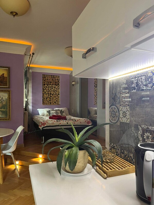Une chambre à coucher moderne avec un lit, une plante en pot et une machine à café.