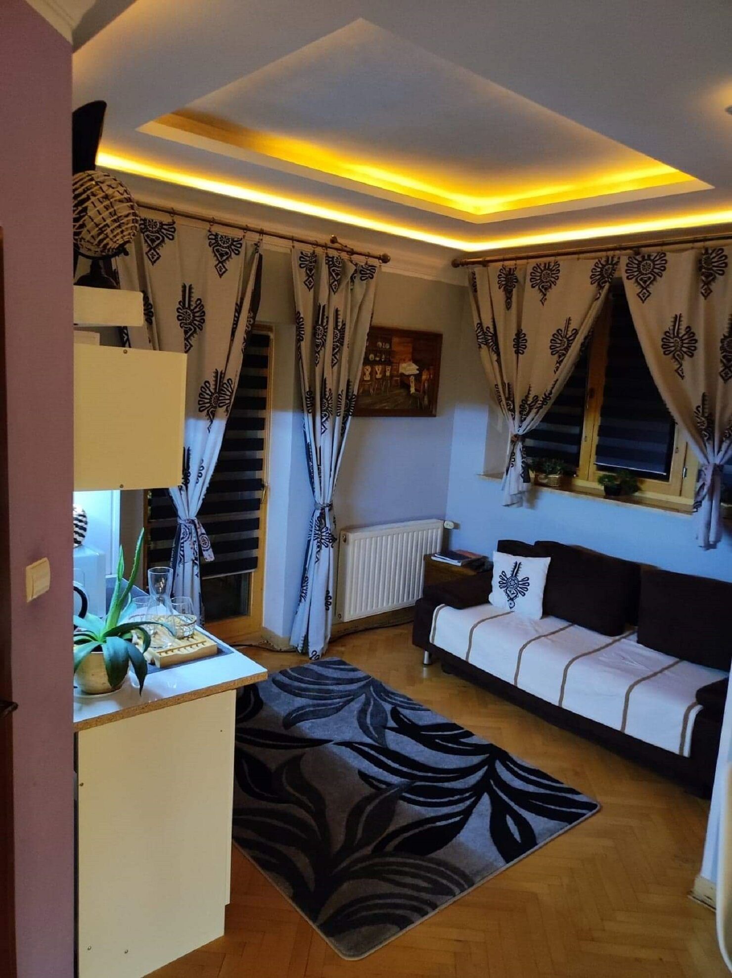 A cozy living room with a sofa, a coffee table, and curtains with a geometric pattern.