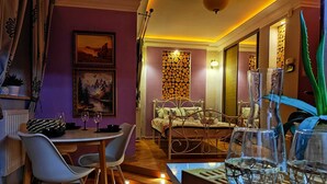 Un salon chaleureux avec un coin repas, doté d’un parquet, d’un canapé, d’une table à manger avec des chaises et d’un escalier menant à une autre pièce.