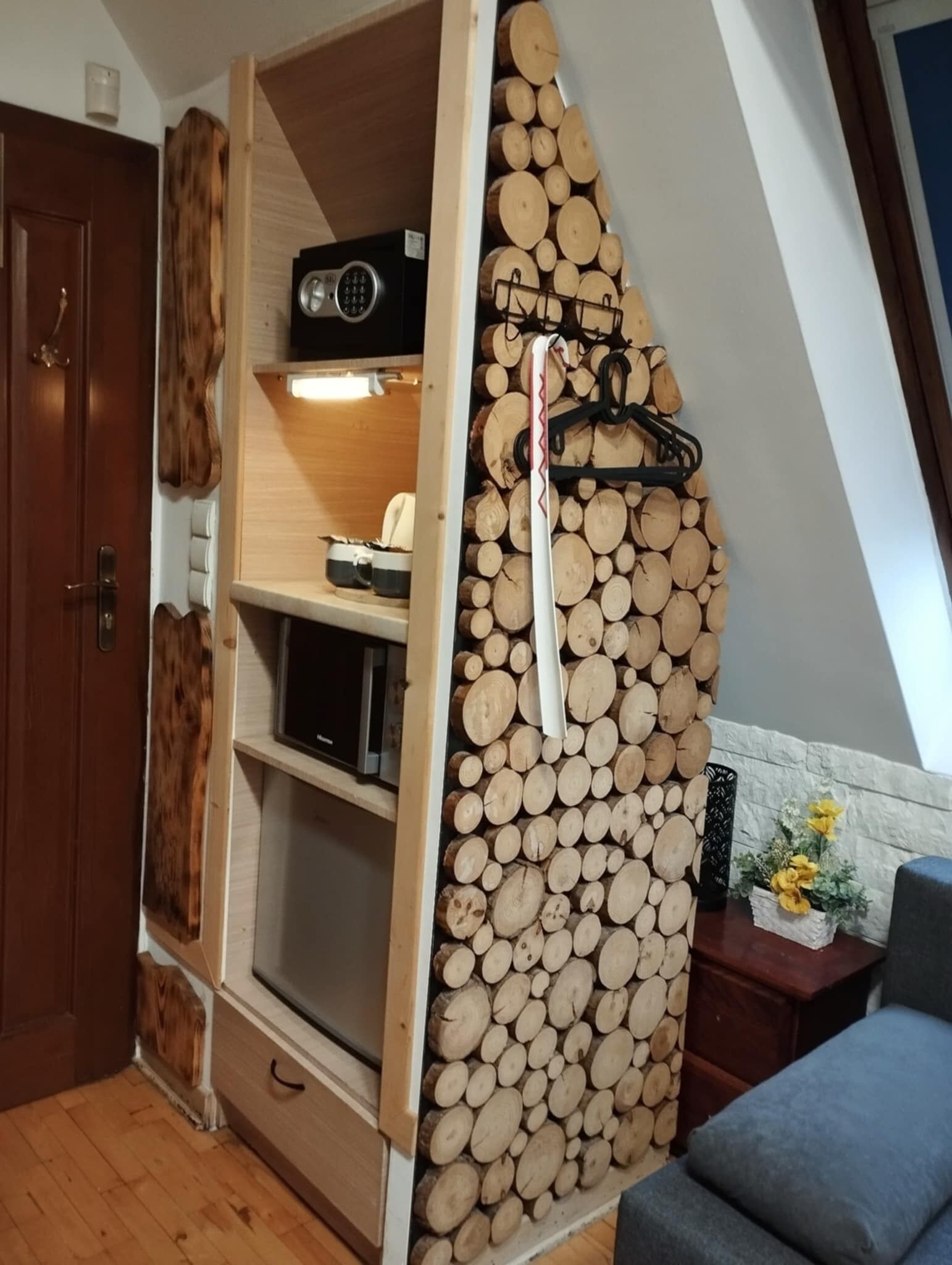 A room with a built-in wooden log wall, a small shelf with a radio, and a cozy seating area with a cushion.