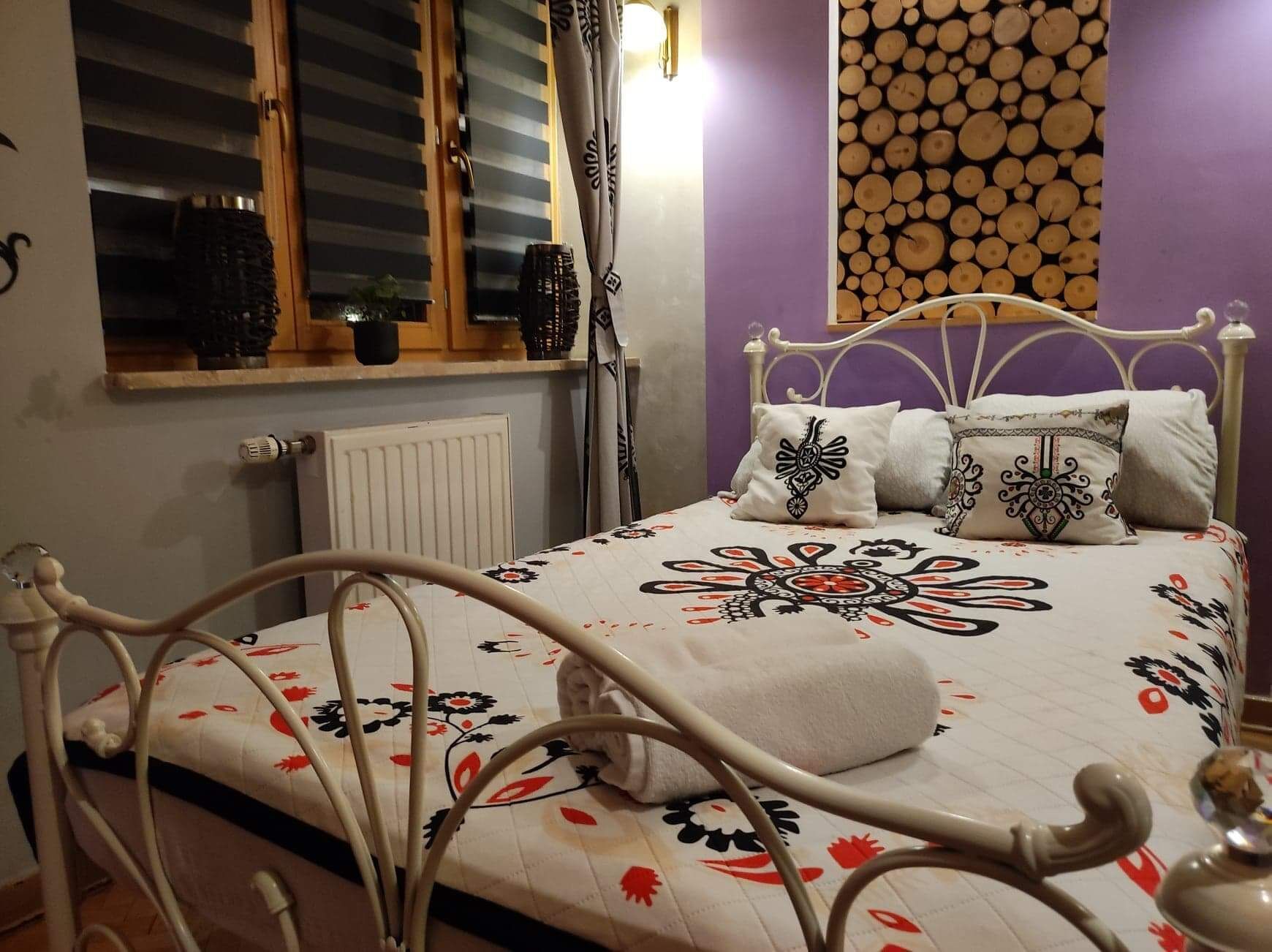 A bed with a floral-patterned bedspread, a white metal headboard, and decorative pillows.