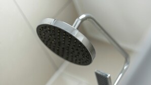 A modern showerhead with a curved design, mounted on a metallic fixture.