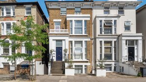 A row of townhouses with front doors, windows, and steps leading to the entrance.