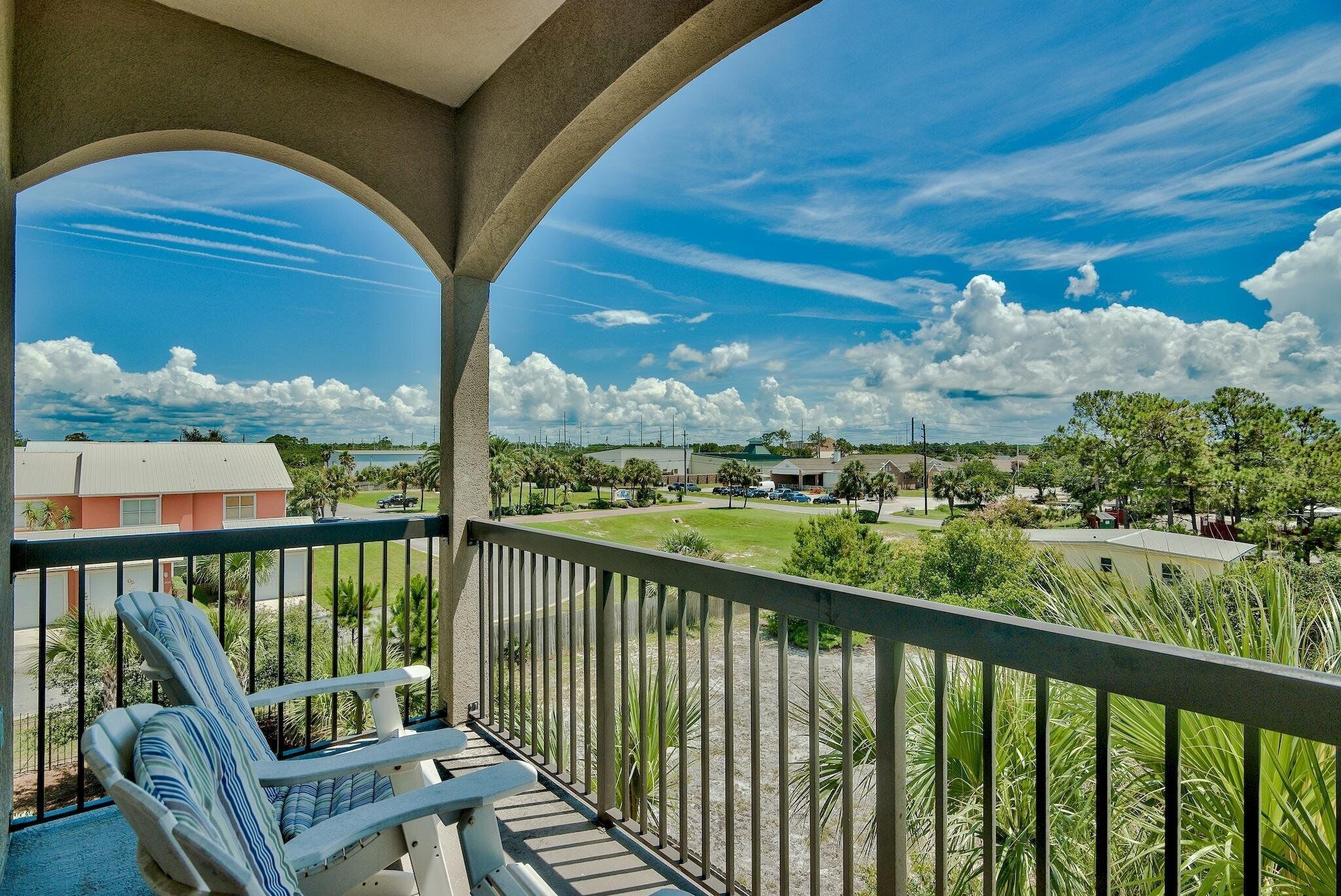 Un balcón con vistas a una zona residencial, con casas y vegetación.