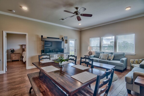 A spacious living area with a dining table, sofa, and a ceiling fan.