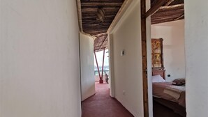 Een smalle gang met een houten plafond en uitzicht op een balkon.
