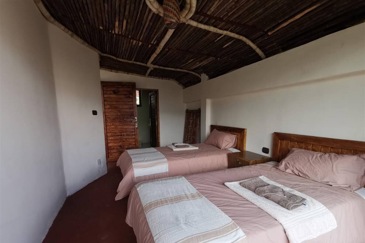 Une chambre avec deux lits, des têtes de lit en bois et un plafond fait de matériaux tressés.