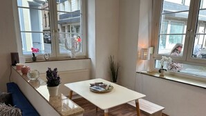 Een moderne woonkamer met een witte tafel, houten vloer en grote ramen.
