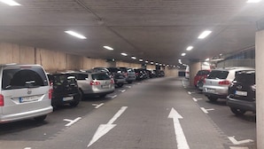 Een parkeergarage met rijen geparkeerde auto's en pijlen op de vloer.