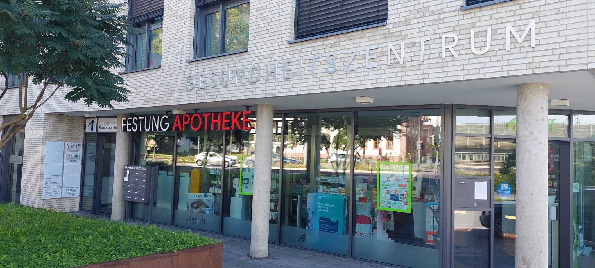Un bâtiment portant une enseigne indiquant  « GESUNDHEITSZENTRUM » et « FESTUNG APOTHEKE », ce qui signifie centre de santé et pharmacie.