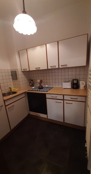 Compact kitchen with modern design, featuring a central island, sink, stove, and coffee maker.