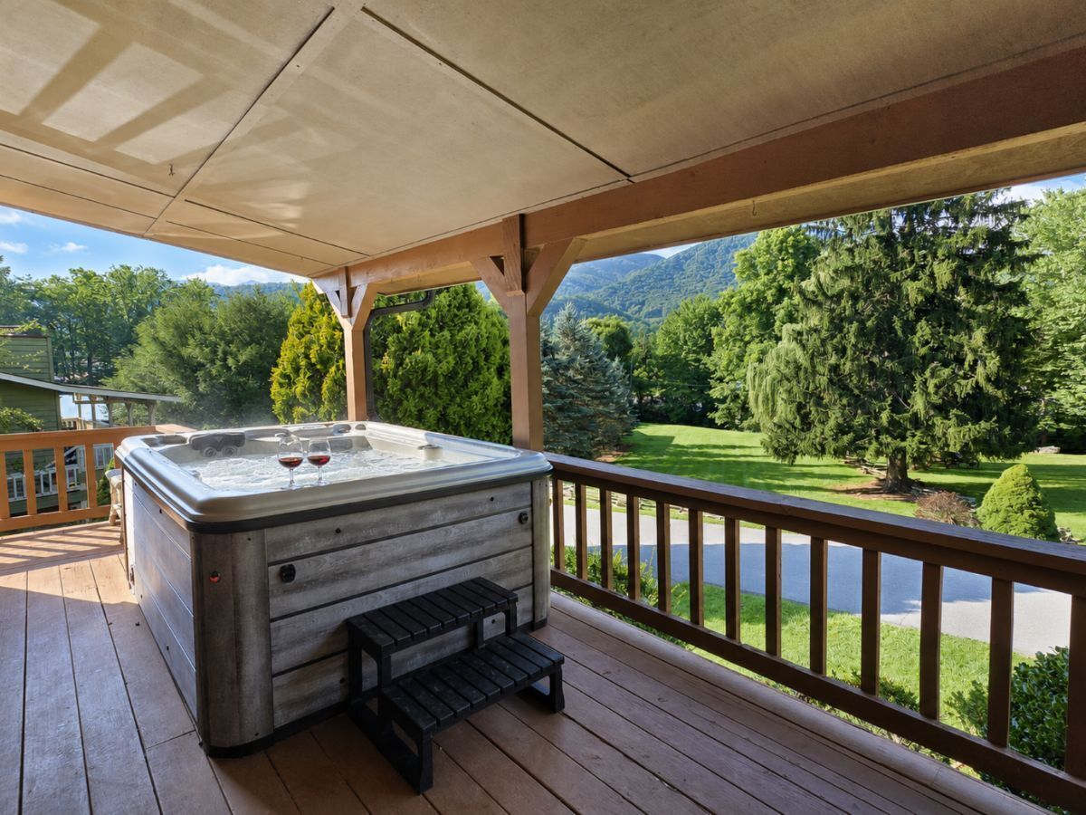 A hot tub on a wooden deck with a view of a golf course and mountains.
