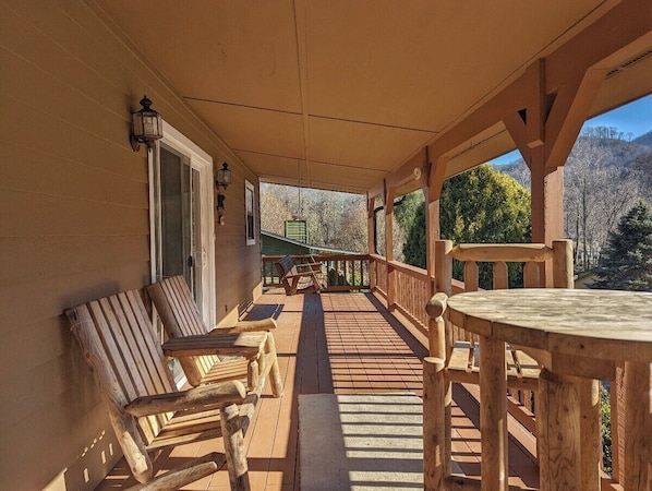 Une terrasse en bois, agrémentée de chaises et d’une table, qui offre une vue sur un paysage montagneux.