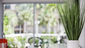 A potted plant on a white table near a window with a view of greenery outside. - The Elmar Boutique Hotel (Lauderdale-by-the-Sea)