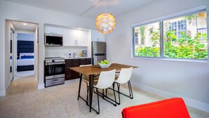 A modern kitchen with white cabinets, a wooden dining table, and a red chair. - The Elmar Boutique Hotel (Lauderdale-by-the-Sea)