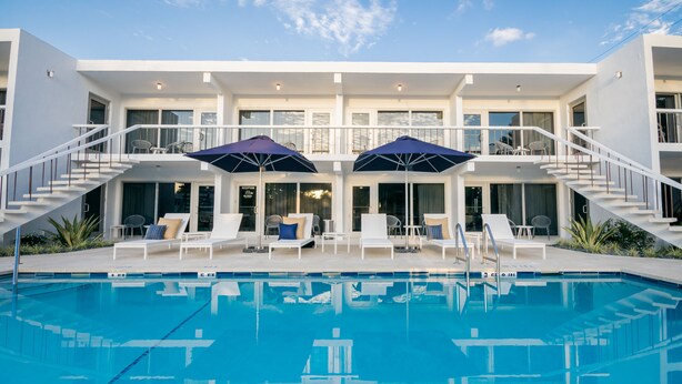 A modern hotel with a swimming pool, outdoor seating, and a staircase leading to the upper floor. - The Elmar Boutique Hotel (Lauderdale-by-the-Sea)