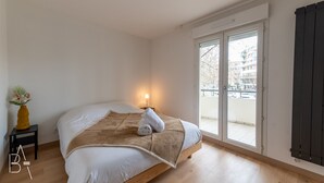 Un dormitori amb un llit, una tauleta de nit amb un vas i una vista per una porta corredissa.