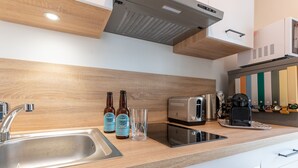 Una cuina moderna amb un rentaplat de formigó inoxidable, dues ampolles de cervesa, un tôster i una cafetera.