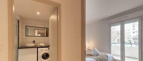Een moderne badkamer met een wastafel, spiegel en wasmachine.