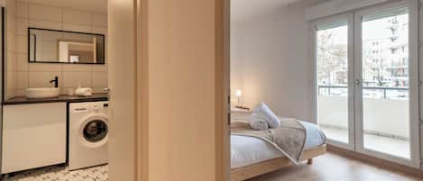 Un apartamento moderno con cocina, lavadora, cama y balcón con vistas.