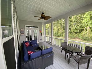A covered porch with a sofa, a table, and chairs. - Coastal Club * 5 BR Luxury Beach House (Lewes)