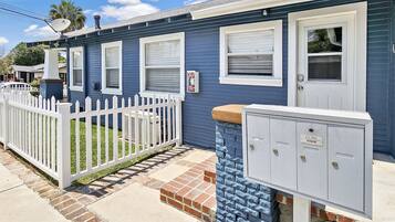 A residential building with a white picket fence, a mailbox, and a utility box.