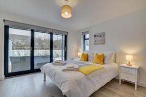 Une chambre avec un grand lit, une table de chevet, une lampe et une vue sur l’extérieur grâce à une porte coulissante.