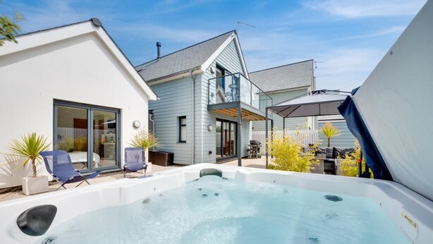 Ein modernes Haus mit Whirlpool, überdachter Terrasse und Garage.