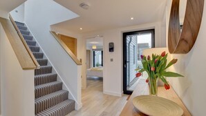 Ein modernes Interieur mit Treppe, Holzboden, Wandspiegel und einer Blumenvase.