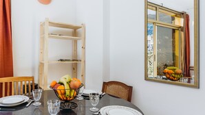 A dining table set with plates, glasses, and cutlery, a fruit bowl, and a wooden shelf. - Le Garibaldi - Studio cosy Sospel (Sospel)