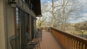 A wooden deck with metal chairs and a table, overlooking a natural landscape with trees and hills. - Williams House at Lake Junaluska -Spacious 5-Bedroom Family Retreat (Lake Junaluska)